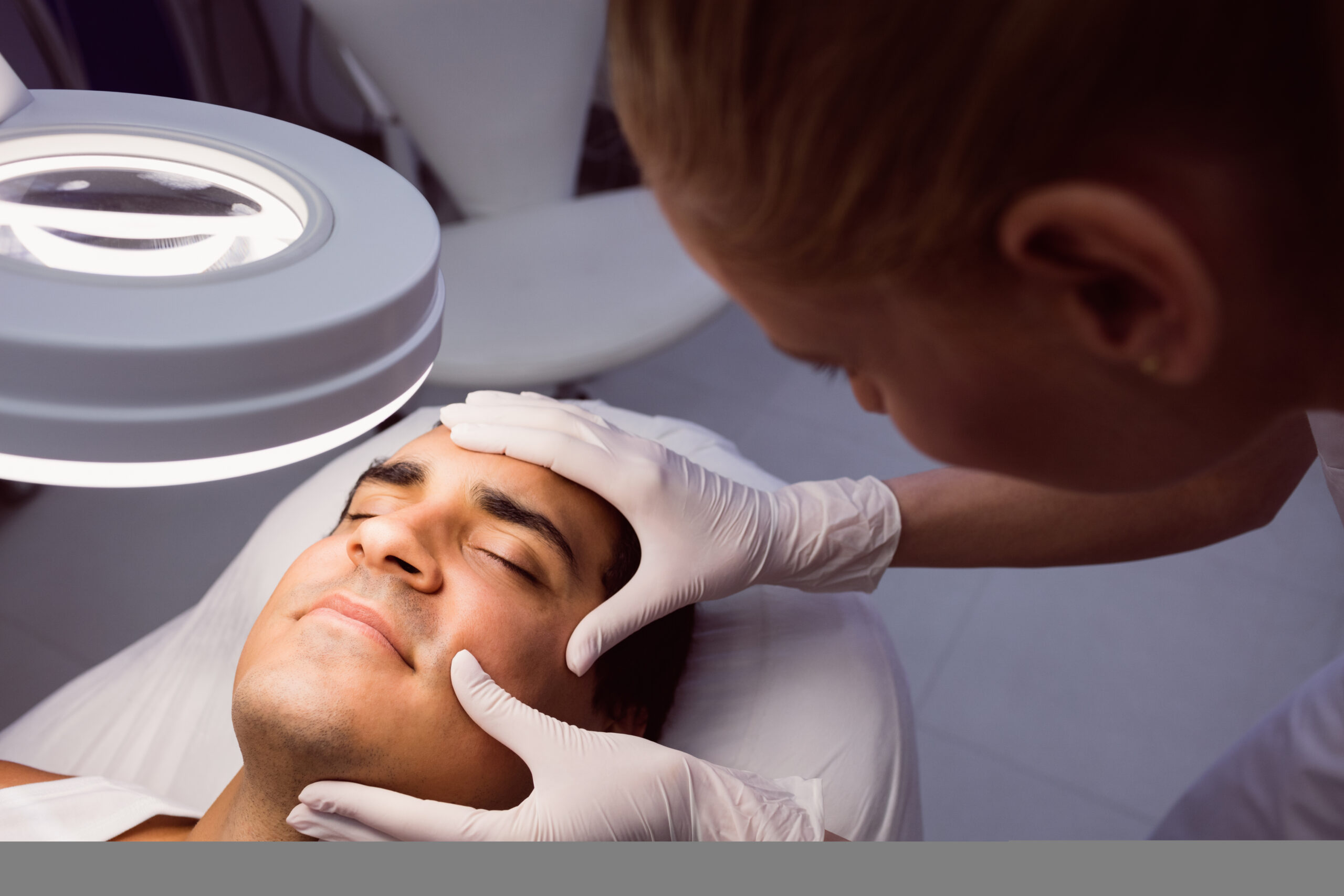 doctor examining mans face for cosmetic treatment at clinic